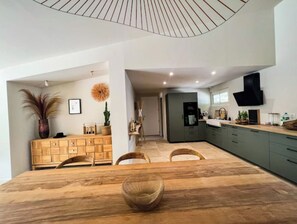 A modern kitchen with a central island, wooden furniture, and a dining area with a large table and chairs.
