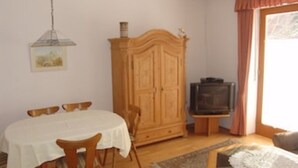 Un coin repas comprenant une table ronde, des chaises, un meuble en bois et un téléviseur.
