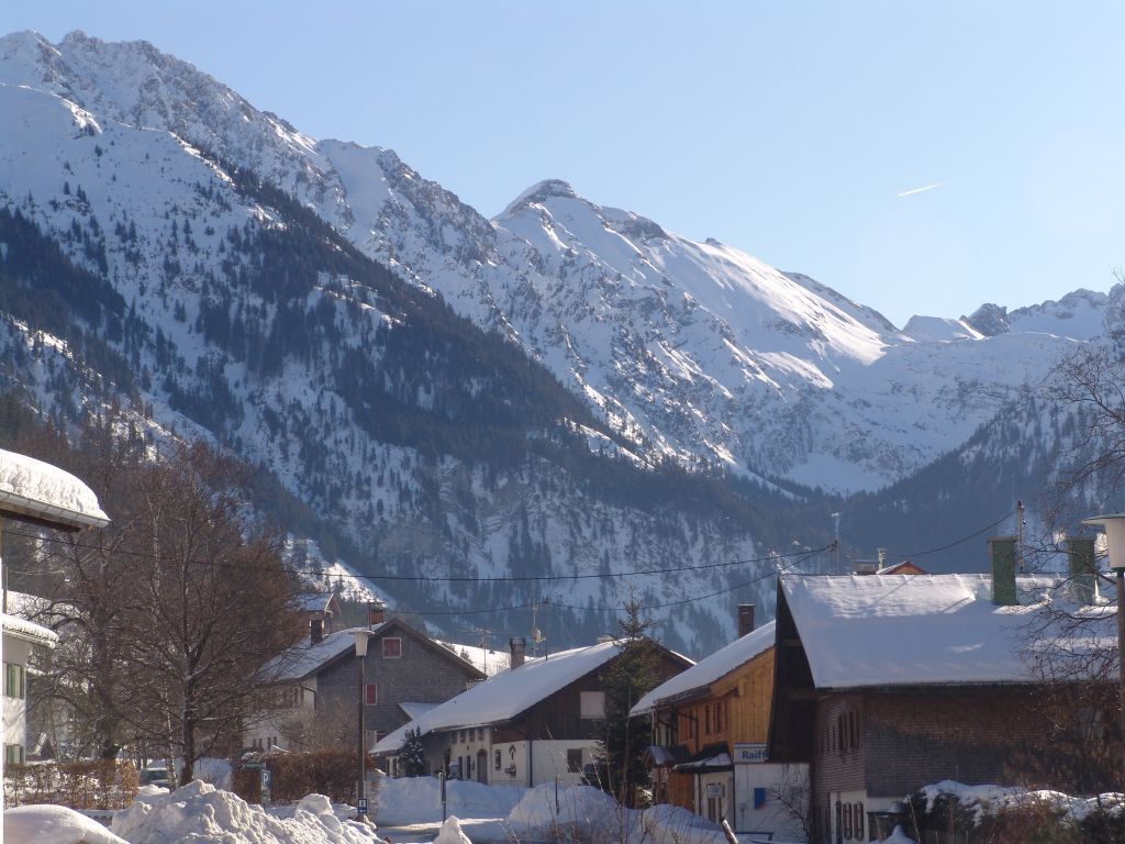 A snow-covered mountain village with traditional wooden houses and a clear view of the mountains.