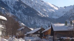 Un village de montagne enneigé, avec des maisons traditionnelles en bois et une vue dégagée sur les montagnes.