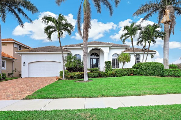 A two-story house with a white facade, a tiled roof, and a front garage.