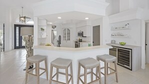 Een moderne keuken met een centraal eiland, barkrukken en inbouwapparatuur.