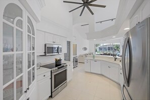 A modern kitchen with white cabinetry, stainless steel appliances, and a large island.