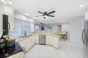 A modern kitchen with a central island, built-in appliances, and a dining area with a wooden table and chairs.