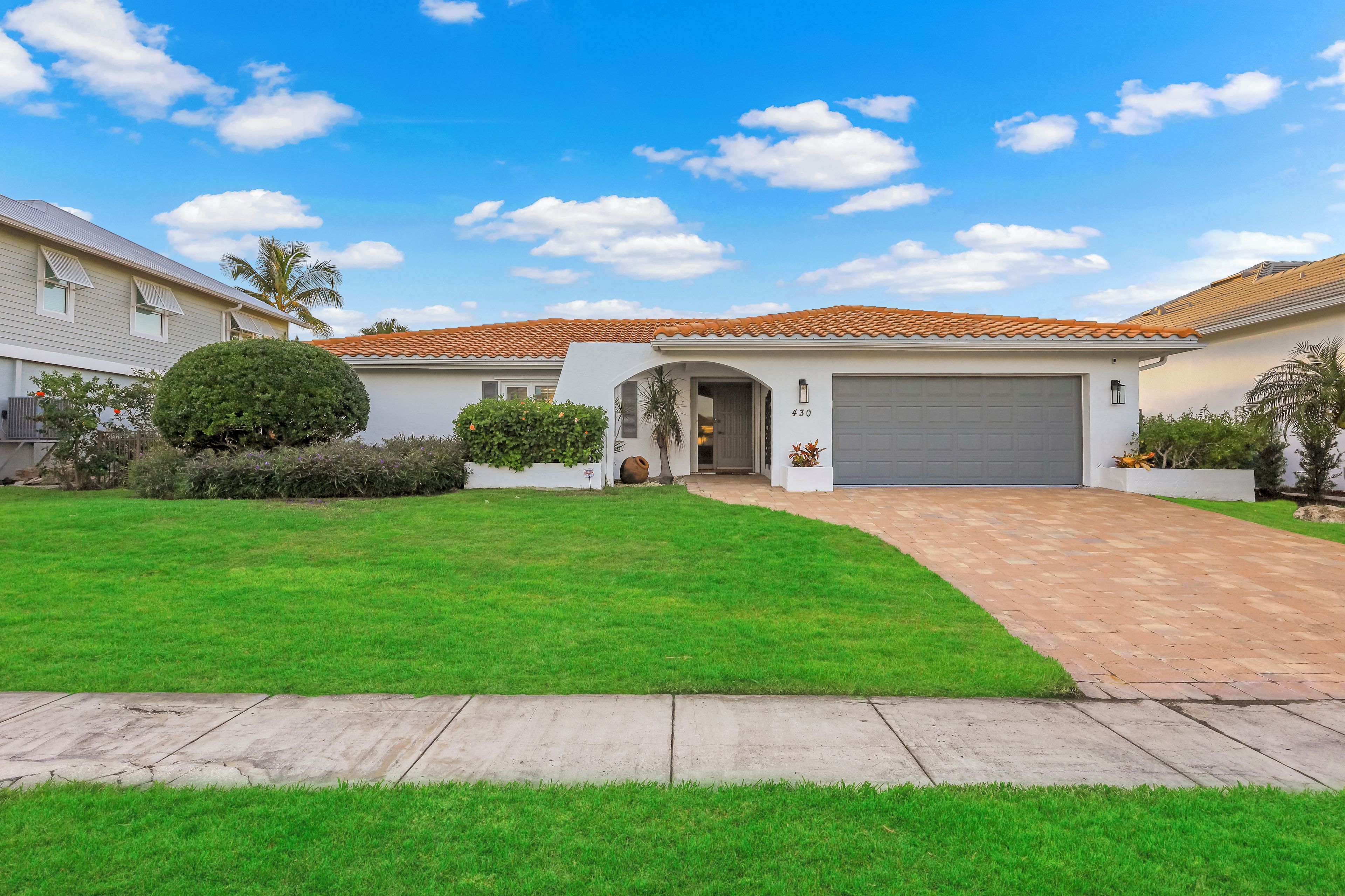 A residential house with a well-maintained lawn, a garage, and a clear sky.