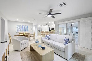 Una sala de estar moderna con sofá, mesa de centro y zona de comedor con sillas y mesa.