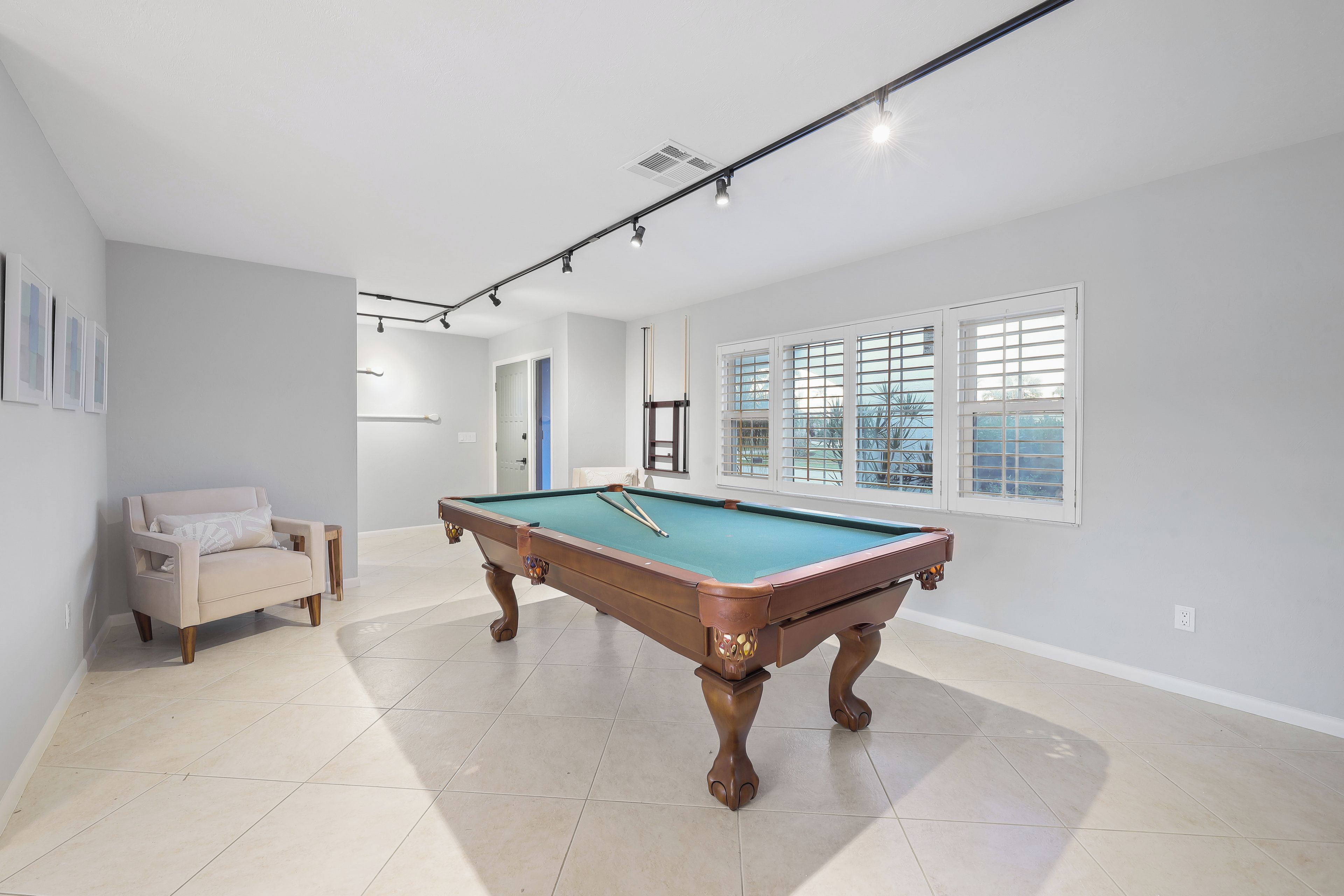 A spacious room with a pool table, a sofa, and large windows.