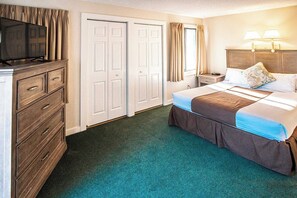 A hotel room with a bed, dresser, TV, and curtains. - Waterwood Townhome (New Bern)