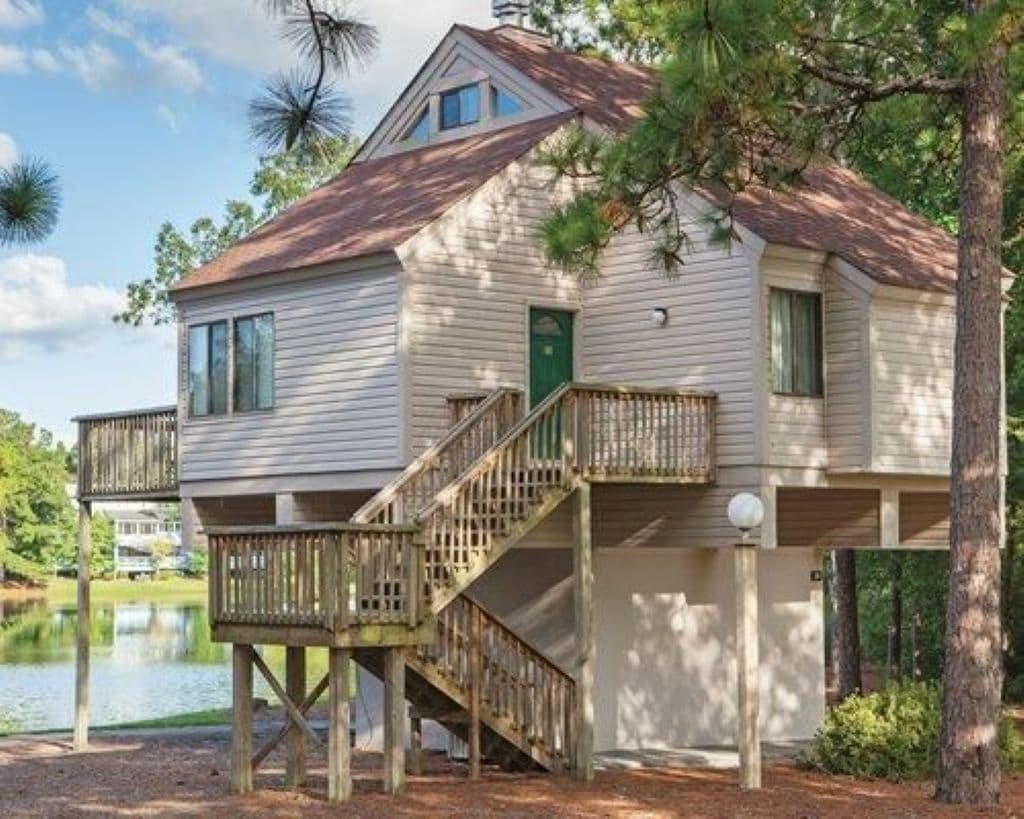 A two-story house with a wooden deck and a staircase leading to the upper level.