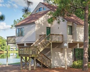 A two-story house with a wooden deck and a staircase leading to the upper level. - Waterwood Townhome (New Bern)