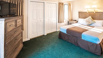 Une chambre d’hôtel comprenant un lit, une commode, un téléviseur et une table de chevet avec des lampes.