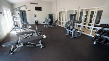 Une salle de sport équipée de divers appareils d’exercice, notamment des bancs et des machines de musculation.