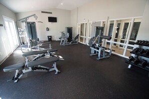 A gym with various exercise equipment, including benches and weight machines. - Waterwood Townhome (New Bern)
