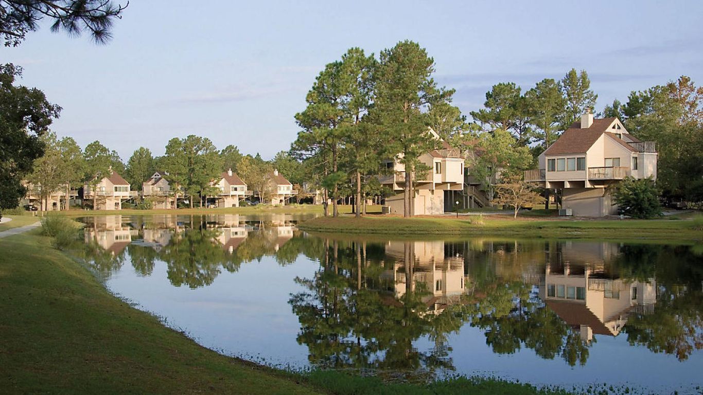 A residential area with houses and a body of water reflecting the buildings.