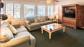 A living room with a sofa, a coffee table, a TV cabinet, and a ceiling fan.