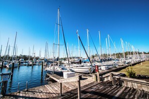 Un puerto deportivo con varias embarcaciones amarradas a muelles de madera bajo un cielo azul despejado.