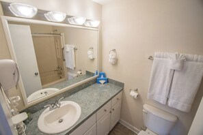 A bathroom with a sink, mirror, towel rack, and toilet. - Waterwood Townhome (New Bern)