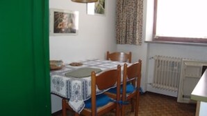 Een eetgedeelte met een tafel gedekt voor twee personen, een radiator en een raam met gordijnen.