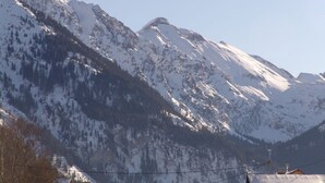 Berglandschap met besneeuwde toppen en enkele gebouwen aan de voet ervan.