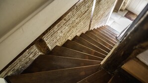 Una escalera de madera con barandilla y una pared con textura a un lado.