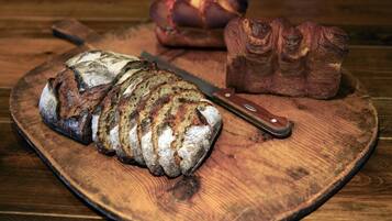 A loaf of bread on a wooden cutting board with a knife.
