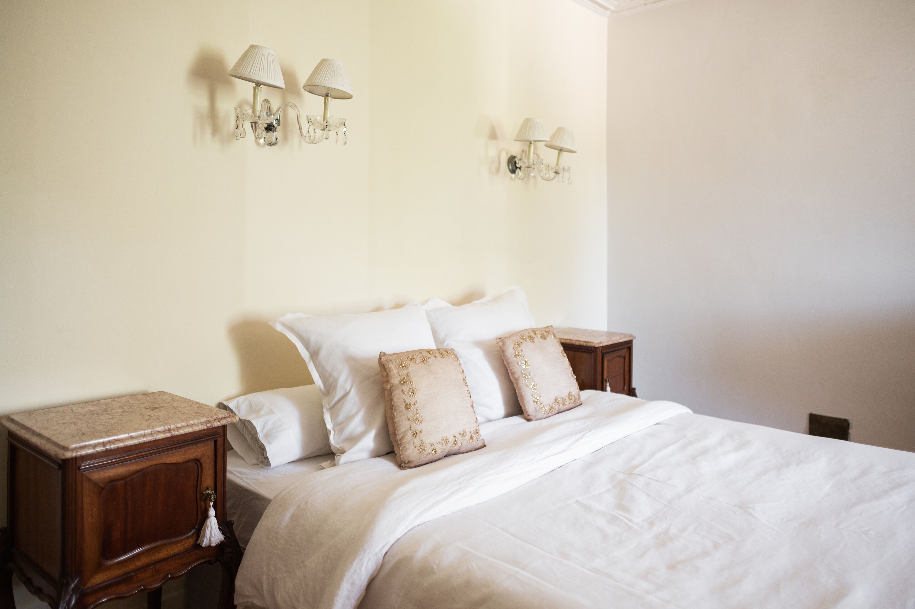 Un dormitorio con una cama, dos mesitas de noche y lámparas de pared.