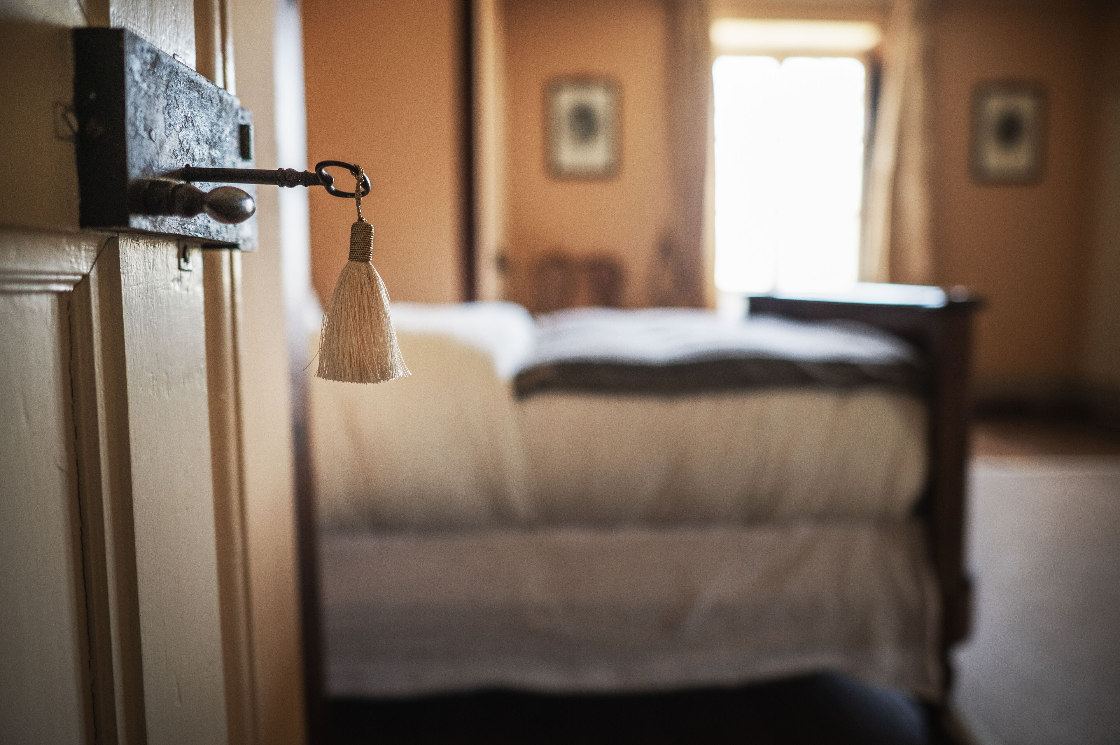 A room with a bed, a door with a keyhole, and a window.