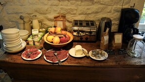 Un bufé de desayuno con diversas opciones de comida, incluyendo carnes, quesos, frutas y bebidas.