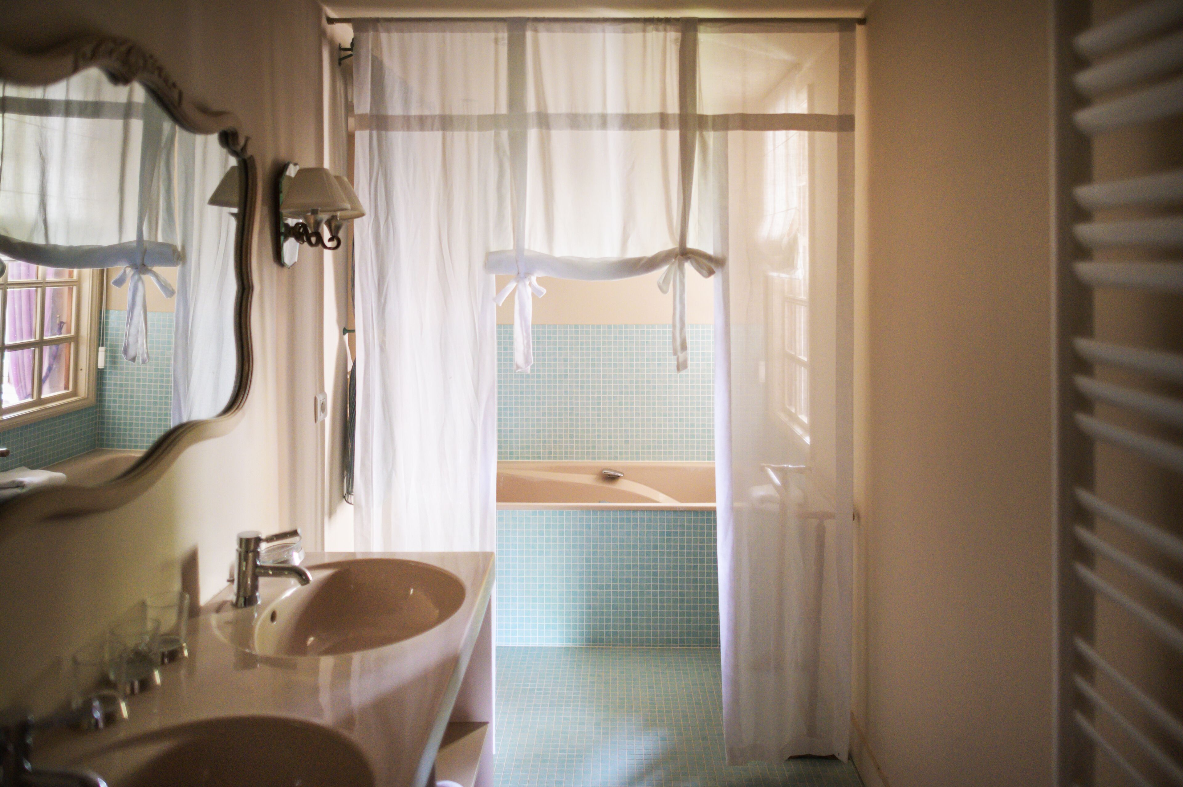A bathroom with a sink, mirror, and bathtub.