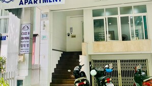 An apartment building named COZI 8 with a sign indicating it's for rent. There are stairs leading to the entrance, and several motorcycles parked in front. - Cozi 8 Apartment (Thành phố Hồ Chí Minh)