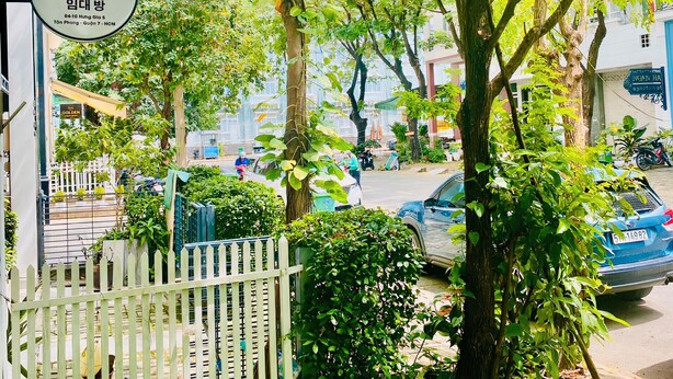 A covered outdoor area with a sign for 'COZI 8 ROOM FOR RENT' and a white picket fence. - Cozi 8 Apartment (Thành phố Hồ Chí Minh)