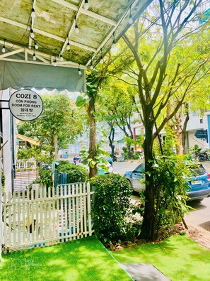 A covered outdoor area with a sign for 'COZI 8 ROOM FOR RENT' and a white picket fence.
