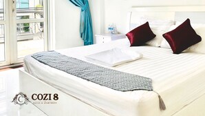 A hotel room with a bed, a nightstand, a window with curtains, and a view of the outside. - Cozi 8 Apartment (Thành phố H ồ Chí Minh)
