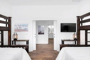 A hotel room with two beds, a TV mounted on the wall, and a door leading to a bathroom. - Sundance: Sleeps 18! 1 Block to Beach! Pool & spa! (Destin)