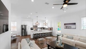 A modern kitchen with stainless steel appliances, a central island with bar stools, and pendant lighting.