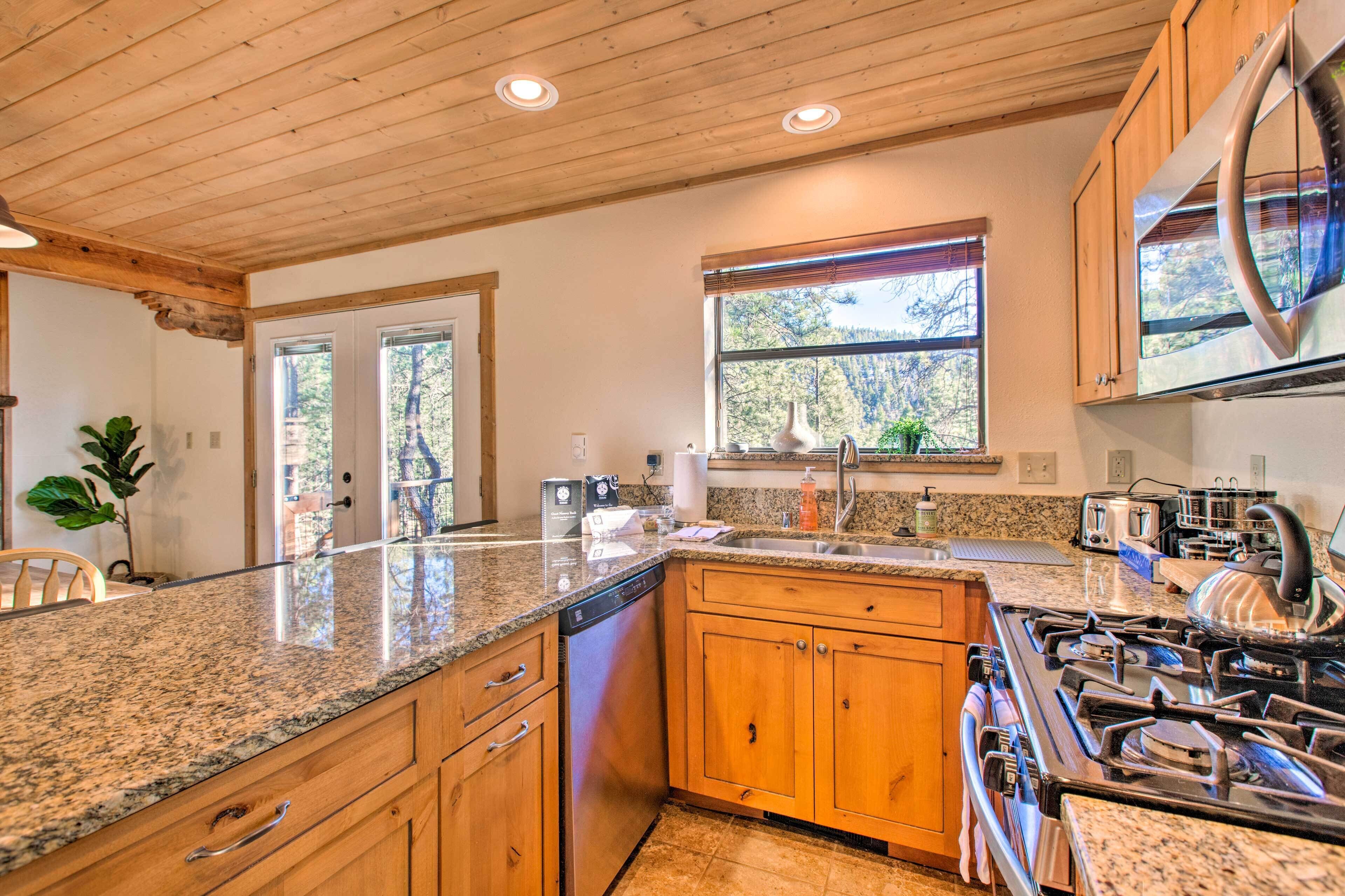 A kitchen with granite countertops, wooden cabinets, a stainless steel range hood, and a window providing natural light.