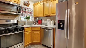 Une cuisine moderne avec des meubles en bois et des appareils en acier inoxydable, notamment un four à micro-ondes, une cuisinière, un lave-vaisselle et un réfrigérateur.
