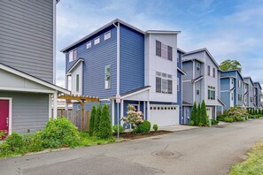 A row of modern townhouses with a covered porch, a garage, and a well-maintained garden.