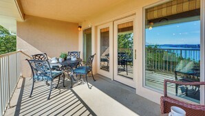 A covered outdoor patio with a table and chairs, a small seating area with a wicker chair, and a view through large glass doors. - 2 Mi to Silver Dollar City: Lakefront Branson Gem! (Branson)
