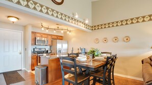 A modern kitchen with wooden cabinets, stainless steel appliances, and a dining area with a wooden table and chairs. - 2 Mi to Silver Dollar City: Lakefront Branson Gem! (Branson)