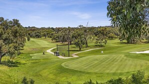 Un campo de golf con un fairway bien cuidado, búnkeres de arena y un putting green.