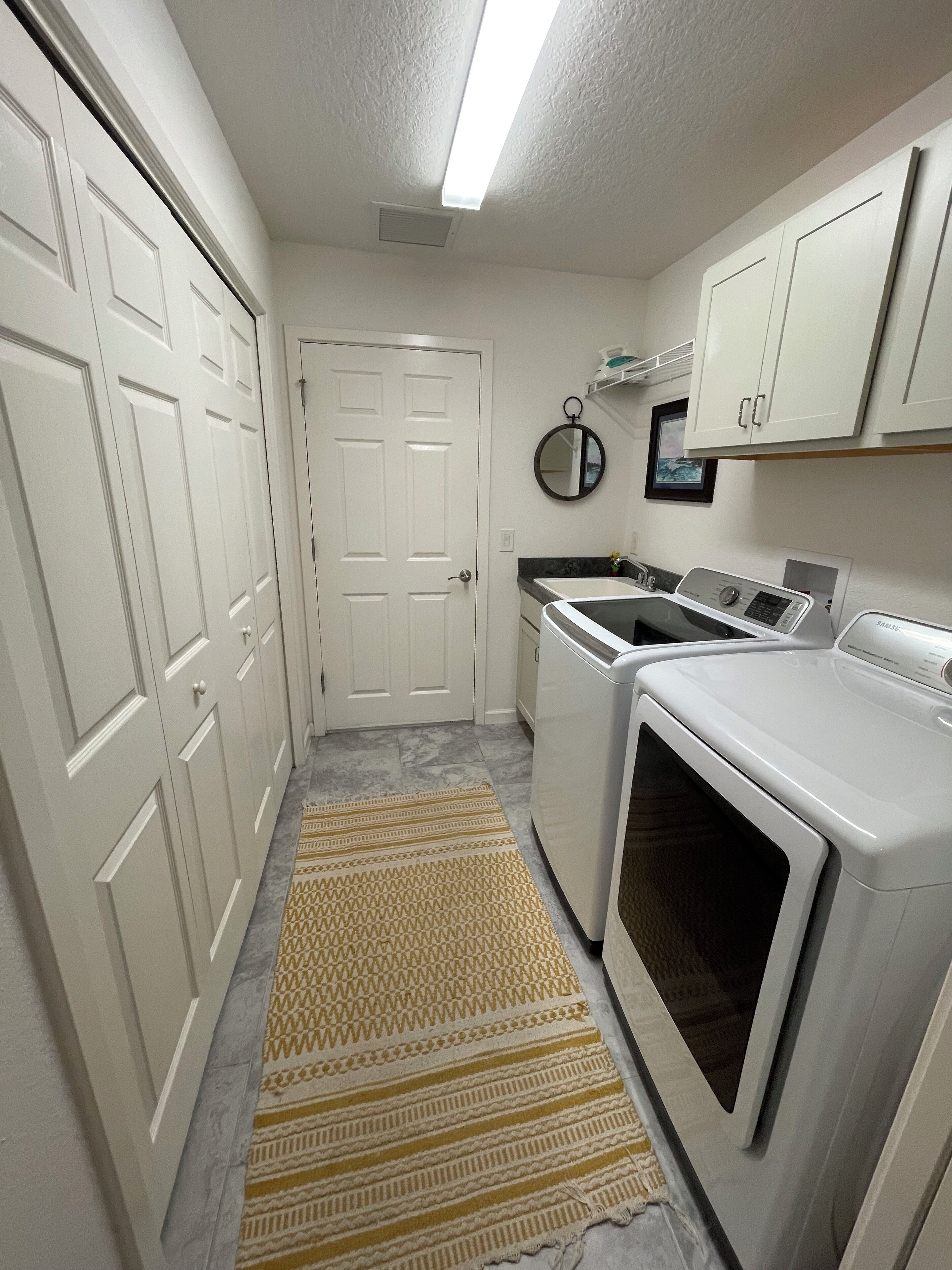 A laundry room with a washing machine, dryer, and a small sink.