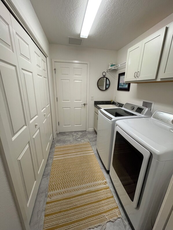 A laundry room with a washing machine, dryer, and a small sink.