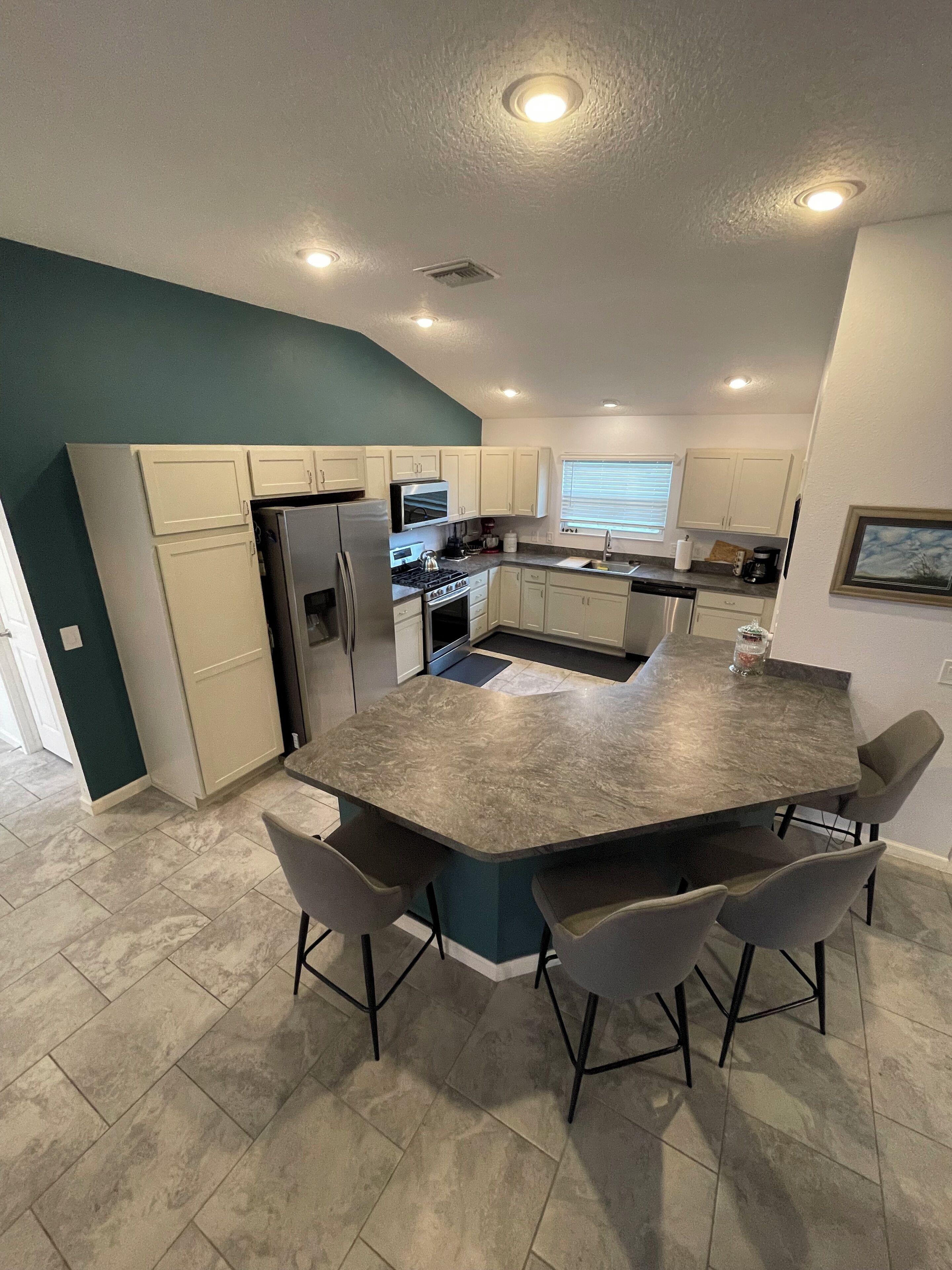A modern kitchen with a central island, bar stools, and built-in appliances.