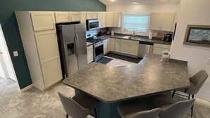 Una cocina moderna con una isla central, taburetes de bar y electrodomésticos integrados.
