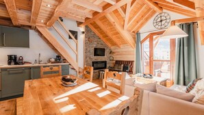 Un intérieur chaleureux en bois, avec une table à manger, des chaises, un canapé, un téléviseur et une cheminée en pierre.