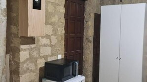 A compact room with a stone wall, a wooden door, and a white wardrobe. - Charming private studio near airport and (Persan)