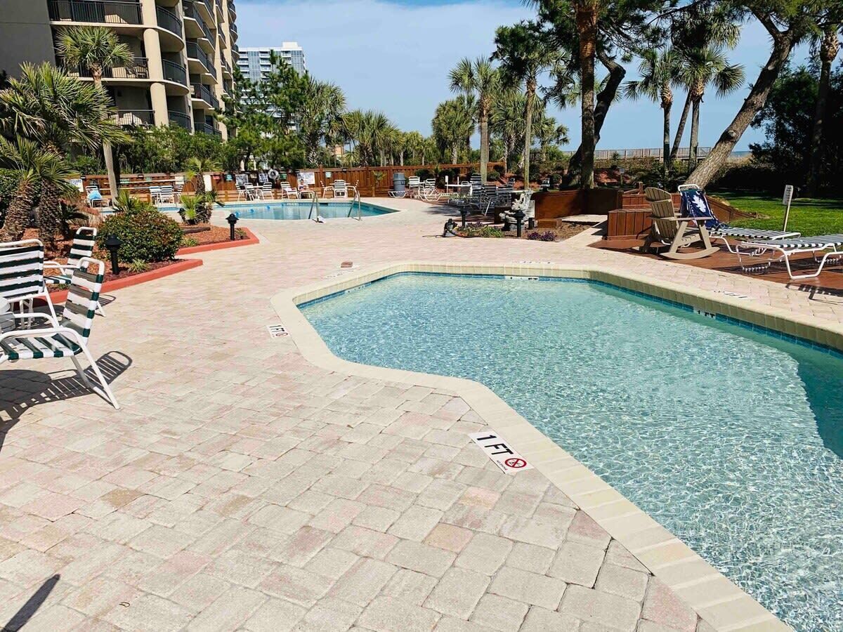 A swimming pool area with lounge chairs and a poolside deck.