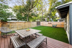 A backyard with a wooden deck, a picnic table, and a chair.