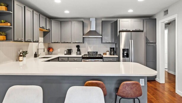 Una cocina moderna con armarios grises, una isla central y un refrigerador de acero inoxidable.